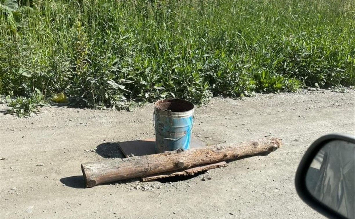 Открытый люк в Южно-Сахалинске прикрыли бревном и пометили ведром