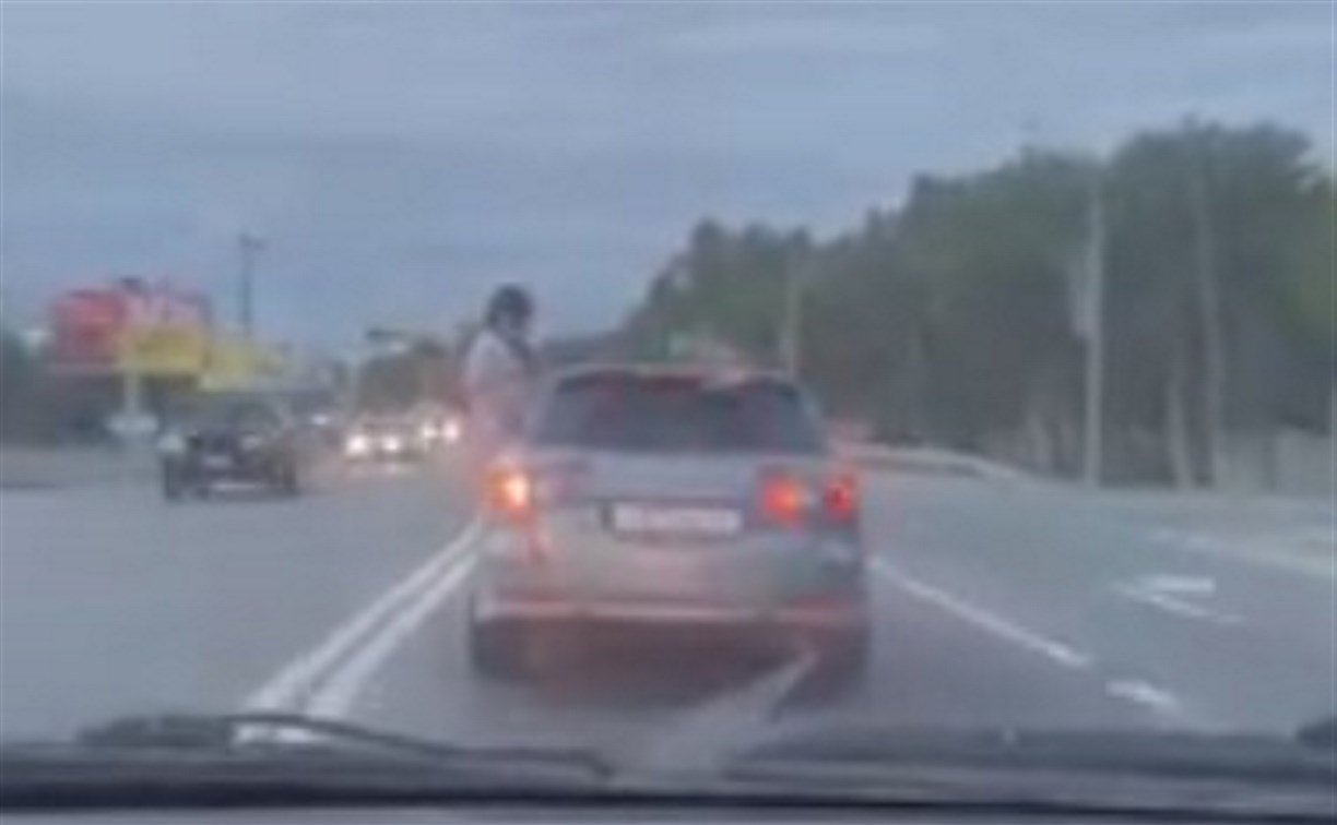 Молодой человек в Южно-Сахалинске наполовину вылез из окна движущегося авто и размахивал руками