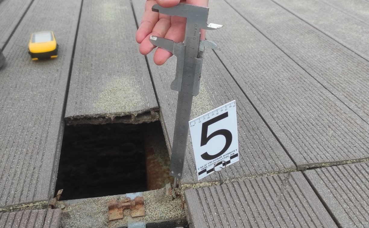 Следком измеряет дыры на деревянной набережной в Охотском