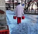 Буфетчицы с вёдрами скользят по ледяной дороге на территории Поронайской ЦРБ